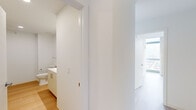 Located at 1400 S Wabash Ave in Chicago's South Loop neighborhood, this single-floor unit is situated at a notable elevation within a contemporary high-rise, offering panoramic views of the city skyline and surrounding urban landscape. The unit is designed with a clean, modern aesthetic throughout, characterized by crisp white walls, light wood flooring, and an abundance of natural light.

The living areas benefit from dramatic floor-to-ceiling glass windows that frame expansive views of Chicago's cityscape, creating a bright and open atmosphere. An exposed concrete structural column adds an industrial architectural detail that complements the otherwise minimalist interior. Roller shades provide optional light control without compromising the view.

The kitchen is well-equipped with warm wood cabinetry, stainless steel appliances including a gas range, built-in microwave, dishwasher, and refrigerator. A white countertop and clean tile backsplash complete the functional and stylish design. Track lighting overhead adds focused illumination.

The bedroom spaces are generously proportioned, each featuring the same light wood flooring and access to city views through large windows. Sliding closet doors provide practical storage solutions. The bathroom presents a streamlined design with a glass-enclosed shower, a long vanity with an integrated sink, and wood-toned cabinetry, all finished in a cohesive, contemporary style.