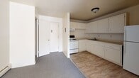 Located at 43 Kenneth St in West Haven, CT, this 2-bedroom, 1-bathroom single-floor unit offers a straightforward and functional layout. The living area is carpeted in neutral grey tones and benefits from natural light through a large window, creating a bright and open feel. Baseboard heating runs along the walls throughout, ensuring efficient warmth. The kitchen is situated adjacent to the living space and features white cabinetry offering ample storage, a white electric range with an overhead exhaust fan, a sink with countertop space, and tile flooring that transitions cleanly from the carpeted areas. A full-size refrigerator completes the kitchen setup. Both bedrooms are carpeted and well-proportioned, each equipped with generous double-door closets featuring built-in shelving and hanging rods for substantial storage capacity. The bathroom includes a tiled shower-tub combination, a vanity sink with a medicine cabinet mirror, and tile accents along the walls. The overall color palette is light and neutral throughout, with cream-toned walls contributing to a clean, move-in ready atmosphere. The unit's single-floor layout provides ease of accessibility and a cohesive flow between all living spaces.