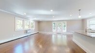 Located at 60 E Linden St in Englewood, NJ, this single-floor home offers a thoughtfully designed layout with clean finishes and a bright, welcoming atmosphere throughout. The expansive main living area is defined by rich hardwood flooring, neutral taupe walls, crisp crown molding, and recessed lighting. French doors open directly to an outdoor deck, framing lush greenery views and filling the space with abundant natural light. The modern kitchen is a standout feature, showcasing white shaker cabinetry, a subway tile backsplash, stone countertops, stainless steel appliances, and a large center island with pendant lighting — ideal for both cooking and entertaining. The bedrooms continue the hardwood flooring theme and are equipped with ceiling fans, recessed lighting, and windows overlooking the surrounding trees. Two bathrooms serve the home: one features large-format marble-look tile flooring, a dark vanity, and a soaking tub, while the second is finished with warm travertine tile, a decorative mosaic border, and a glass-enclosed shower. The consistent use of quality materials and neutral tones throughout creates a cohesive and polished aesthetic, making this Englewood home a comfortable and functional residence.
