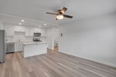 Located in Temecula, CA, this efficiently designed one-bedroom, one-bathroom unit offers a clean, modern aesthetic throughout its well-utilized single floor. Light wood-style luxury vinyl flooring flows seamlessly through every room, creating a cohesive and bright interior.

The open-concept kitchen and living area serves as the heart of the unit. The kitchen is outfitted with crisp white shaker cabinetry, a suite of stainless steel appliances including a refrigerator, electric range, microwave, and dishwasher, and a white quartz-topped peninsula that provides both additional prep space and casual seating. Recessed lighting illuminates the space, while a ceiling fan in the living area adds comfort and airflow.

The bedroom is a calm, light-filled retreat, featuring a ceiling fan, a large window framing views of surrounding greenery, and a dedicated closet for ample storage. Natural light pours in generously, enhancing the room's airy feel.

The bathroom is finished in a clean, contemporary style with white shaker cabinetry, a white quartz countertop, a large mirror, and a walk-in shower with sliding glass doors and a built-in grab bar. Recessed lighting completes the polished look.

A dedicated closet off the kitchen provides additional storage, making this unit as functional as it is attractive.