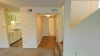 This two-story home offers a practical and well-organized layout designed for comfortable everyday living. The interior is finished in a clean, neutral palette throughout, creating a bright and welcoming atmosphere. Hardwood flooring runs through the hallway and main living areas on the lower level, adding warmth and durability underfoot, while plush carpeting lines the staircase that connects the two floors. The hallway serves as a central corridor, efficiently linking the various rooms and featuring flush-mount ceiling lighting and dual HVAC vents to ensure consistent climate control throughout. White painted walls and trim provide a crisp, timeless look that complements any décor. Doors along the hallway lead to additional rooms, including what appears to be a bathroom, offering functional accessibility throughout the home. The staircase, positioned conveniently off the main corridor, features carpeted treads for comfort and safety. Overall, the space presents a move-in ready environment with a straightforward, functional design, well-suited for those seeking a clean and unpretentious home across two thoughtfully connected levels.