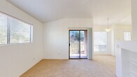 Located at 201 S Camino Seco in Tucson, Arizona, this single-story, one-bedroom, one-bathroom residence offers a well-organized layout with a bright and airy feel throughout. The combined living and dining area is a standout space, highlighted by vaulted ceilings, soft carpeting, and generous natural light from multiple windows and a sliding glass door that opens to an outdoor view. A tile-surround wood-burning fireplace serves as the focal point of the living area, flanked by built-in shelving for added functionality and character. The kitchen is efficiently designed with wood-accented cabinetry, white countertops, a double sink, and a full suite of appliances including a stove, microwave, and refrigerator. A peninsula counter with a pendant light overhead provides a natural transition to the dining space. The bedroom is a comfortable, carpeted retreat with a window that brings in natural light and connects via a hallway to the rest of the home. The bathroom features wood-look vinyl flooring, a vanity with countertop storage, and a full tub-shower combination. Clean white walls and consistent finishes throughout create a cohesive, move-in ready environment well-suited for Tucson living.