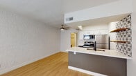 This single-floor unit offers a thoughtfully designed layout that balances functionality with modern style. The open-concept living and kitchen area serves as the heart of the space, featuring light wood laminate flooring that flows seamlessly throughout the main living zones. A ceiling fan overhead adds a practical touch to the living area, which is bathed in natural light.

The kitchen is a standout feature, equipped with stainless steel appliances including a range, over-the-range microwave, and a full-size refrigerator. Crisp white cabinetry with dark hardware provides ample storage, while the peninsula countertop with a white surface offers both prep space and casual seating. A bold patterned tile accent wall adds a decorative focal point near the kitchen, complemented by open wood shelving for display or additional storage.

The entry area is bright and welcoming, with a window allowing natural light to filter in. The bedroom features plush carpeting, a window with blinds for natural light and privacy, and a mirrored sliding closet for generous storage. The bathroom is clean and contemporary, showcasing a wide white countertop vanity with an undermount sink, sleek black-framed cabinetry, and mirrored medicine cabinets above. The overall ambiance is fresh, neutral, and move-in ready.