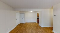 This single-floor residence offers a well-organized layout designed for comfortable everyday living. The main living area is bright and open, featuring warm hardwood-style flooring that extends throughout the common spaces. White walls and clean baseboards give the area a fresh, neutral aesthetic. A front entry closet with louvered bi-fold doors provides convenient storage upon entry, while a dedicated thermostat keeps the space climate-controlled year-round.

The galley-style kitchen is efficiently arranged with warm honey-toned wood cabinetry lining both sides, dark speckled countertops, a stainless steel double sink, and black appliances including a full-size refrigerator. The hardwood-style flooring continues seamlessly into the kitchen, maintaining a cohesive look throughout.

A secondary living or flex space opens to the outdoors through a large sliding glass door dressed with vertical blinds, allowing generous natural light to fill the room and providing direct outdoor access.

The bedroom is a quiet, carpeted retreat with a window fitted with vertical blinds, offering both natural light and privacy. Neutral tones throughout keep the room calm and versatile.

The bathroom is clean and functional, featuring a full-size soaking tub with a tiled shower surround and a chrome curtain rod, completing this practical and move-in-ready residence.