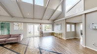 Located at 9071 Mill Creek Rd in Levittown, PA, this single-story amenity and fitness center offers a generously sized, thoughtfully designed layout ideal for an active community. The entrance welcomes visitors with a bright, open foyer finished in elegant tile flooring and leads into a hallway connecting the various areas of the facility.

The main lounge area makes an immediate impression with soaring vaulted ceilings accented by exposed beams and an abundance of natural light streaming through large windows and clerestory glazing above. Comfortable seating arrangements, warm wood-look flooring with geometric inlay accents, and wall-mounted displays create an inviting gathering space. Views toward an outdoor pool area are visible through glass doors, seamlessly connecting interior and exterior.

The fitness center is a standout feature, boasting dramatic vaulted ceilings with skylights, bold teal and grey graphic wall murals, and a vibrant striped floor. It is equipped with a comprehensive array of cardio machines, strength equipment, and free weights, with multiple wall-mounted screens throughout. Ceiling fans and arched windows overlooking the pool enhance the energetic atmosphere.

A glass-enclosed studio room with floor-to-ceiling mirrors provides a versatile space for group classes or personal training. A private office with warm hardwood flooring rounds out the facility, offering a quiet professional setting within this dynamic community hub.