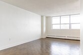 Located at 3434 Eglinton Ave E in Toronto's Scarborough neighbourhood, this 2-bedroom, 1-bathroom unit offers a clean, functional layout spread across a single floor. The living room is a standout feature, boasting expansive floor-to-ceiling windows that flood the space with natural light and provide open views of the surrounding neighbourhood. Classic parquet hardwood flooring runs throughout the living and bedroom areas, adding warmth and character to the bright, white interior.

The primary bedroom is a well-proportioned retreat, complete with a full sliding-door closet for ample storage. The second bedroom also features parquet flooring and easy hallway access, making it well-suited as a guest room or home office. A central hallway connects all rooms efficiently.

The kitchen has been thoughtfully updated with white shaker-style cabinetry, dark countertops, a double undermount stainless steel sink, a modern pull-down faucet, and a marble-style subway tile backsplash. Light tile flooring completes the fresh, contemporary look. A stainless steel refrigerator is included.

The bathroom is similarly renovated, featuring large-format floor tiles, a white vanity, and a tub-shower combination with classic white subway tile surround. Throughout, the unit maintains a crisp, neutral palette that is move-in ready.