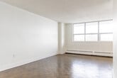 Located at 3434 Eglinton Ave E in Toronto's Scarborough neighbourhood, this 2-bedroom, 1-bathroom unit offers a clean, functional layout spread across a single floor. The living room is a standout feature, boasting expansive floor-to-ceiling windows that flood the space with natural light and provide open views of the surrounding neighbourhood. Classic parquet hardwood flooring runs throughout the living and bedroom areas, adding warmth and character to the bright, white interior.

The primary bedroom is a well-proportioned retreat, complete with a full sliding-door closet for ample storage. The second bedroom also features parquet flooring and easy hallway access, making it well-suited as a guest room or home office. A central hallway connects all rooms efficiently.

The kitchen has been thoughtfully updated with white shaker-style cabinetry, dark countertops, a double undermount stainless steel sink, a modern pull-down faucet, and a marble-style subway tile backsplash. Light tile flooring completes the fresh, contemporary look. A stainless steel refrigerator is included.

The bathroom is similarly renovated, featuring large-format floor tiles, a white vanity, and a tub-shower combination with classic white subway tile surround. Throughout, the unit maintains a crisp, neutral palette that is move-in ready.