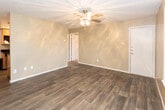 Located at 2102 W Loop 289 Frontage Rd in Lubbock, Texas, this single-floor unit offers a practical and well-appointed layout throughout. The main living area features dark wood-look plank flooring that extends through the entry and common spaces, complemented by neutral-toned walls and a textured ceiling. A decorative light fixture anchors the living room, which receives natural light through a window fitted with blinds and connects seamlessly to the rest of the unit via an open entryway.

The galley-style kitchen is efficiently designed with warm wood cabinetry, dark granite-look countertops, and a full suite of stainless steel appliances including a refrigerator, electric range, and over-the-range microwave. The layout maximizes storage with upper and lower cabinets lining both sides of the kitchen.

The bedroom is carpeted for added comfort and includes a ceiling fan with light, a window for natural light, and ample wall space. The full bathroom features a vanity with a dark granite-style countertop, wood cabinetry above, a toilet, and a tiled shower-tub combination. Throughout the unit, consistent finishes and neutral tones create a cohesive and functional living environment.
