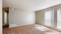 This single-floor unit offers a functional and practical layout designed to maximize everyday comfort. The living area is generously proportioned, featuring warm neutral-toned carpeting, textured walls painted in soft beige, and a textured ceiling. A large window with vertical blinds allows natural light to pour in, casting bright patterns across the floor and creating an open, airy atmosphere. Ceiling-mounted HVAC vents ensure year-round climate control throughout the space.

The galley-style kitchen is well-equipped with stainless steel appliances, including a range and refrigerator, complemented by a dishwasher. Gray cabinetry lines both sides of the kitchen, offering ample storage, while light-toned countertops and a tile backsplash add a clean, modern touch. Light wood-style flooring runs the length of the kitchen, providing a durable and easy-to-maintain surface.

The bedroom is a comfortable, carpeted retreat with neutral walls, good overhead ventilation, and multiple electrical outlets for convenience. The bathroom features a full-size soaking tub with a tiled surround, a shower, and wood-style flooring that ties together the overall aesthetic. Clean white fixtures and chrome hardware complete the look, giving the bathroom a crisp, functional finish throughout.