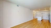 Located at 1905 Champs Drive in Naples, FL, this well-designed one-bedroom, one-bathroom unit offers a clean, modern aesthetic throughout its efficiently organized single-floor layout. Light wood-tone flooring runs continuously across all rooms, lending warmth and visual cohesion to the entire space.

The open-concept kitchen and living area serves as the heart of the unit. The kitchen is outfitted with white shaker-style cabinetry, quartz countertops, a subway tile backsplash, and a full suite of stainless steel GE appliances including a side-by-side refrigerator with ice and water dispenser, a slide-in electric range, an over-the-range microwave, and a dishwasher. A central kitchen island provides additional prep and dining space.

The living area is bright and open, offering a flexible layout for various furniture arrangements. The bedroom is a comfortable, well-proportioned retreat featuring a ceiling fan, a window with outdoor views, and access to a dedicated walk-in closet fitted with wire shelving for organized storage.

The full bathroom is finished in a crisp, all-white palette with subway tile surround, a soaking tub with shower, a single-sink vanity with quartz countertop, and a large mirror. A dedicated laundry room houses a full-size top-loading washer and dryer with overhead shelving, adding practical convenience to the layout.