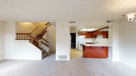 This two-story residence offers a well-organized layout across two levels. The main floor centers around a carpeted living room, highlighted by a tile-surround fireplace and sliding glass doors that invite natural light and provide access to an outdoor area. Adjacent to the living room, the kitchen is equipped with rich reddish-brown cabinetry, light countertops, a double stainless steel sink, a white electric range, and a dishwasher. Light hardwood-style flooring runs through the kitchen, while a breakfast bar peninsula connects the space to the main living area. A staircase with wood railings leads to the upper level. The two bedrooms upstairs are carpeted and well-lit by multiple windows with outdoor views. One bedroom features mirrored sliding closet doors, while another includes direct access to a private bathroom. The bathrooms are finished with wood-toned vanity cabinetry, light countertops, and tub-shower combinations. A half bathroom is also available, rounding out the 2.5-bath configuration. Textured ceilings are consistent throughout, contributing to a cohesive aesthetic across the home.