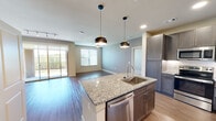 This well-appointed 2-bedroom, 3-bathroom residence in Round Rock, TX offers a thoughtfully designed single-floor layout that maximizes comfort and functionality. The open-concept living and kitchen area serves as the heart of the home, where rich hardwood-style flooring flows seamlessly throughout. The kitchen is a standout feature, boasting a large granite-topped island with a stainless steel sink, dark espresso shaker cabinetry, a subway tile backsplash, and stainless steel appliances including a French-door refrigerator. Stylish pendant lighting illuminates the island, adding a modern touch. The living area is bright and airy, benefiting from natural light through large windows and a sliding glass door that opens to a private outdoor balcony. The generously sized primary bedroom features hardwood-style flooring, a ceiling fan, and access to a walk-in closet with built-in shelving. The secondary bedroom offers plush carpeting, a ceiling fan, and a sun-filled window. The bathrooms are elegantly finished, with one featuring a frameless glass walk-in shower adorned with large-format tile. Two dedicated closets provide ample storage throughout the residence.