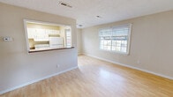 Located at 1212 W Ocean View Ave in Norfolk, Virginia, this two-bedroom, one-bathroom single-floor home offers a practical and functional layout. The open living and dining area is finished with light wood laminate flooring that extends throughout the main living spaces, lending a clean and bright aesthetic. A large window allows natural light to fill the room, creating an airy feel. The kitchen features white cabinetry, a stainless steel dishwasher, a white refrigerator, and a pass-through counter that connects it to the dining area, promoting an open and accessible flow. A hallway connects the main living areas to the private quarters, which include three closets for ample storage. Both bedrooms are carpeted and finished with neutral tones; the primary bedroom includes a ceiling fan, a window with natural light, and a dedicated closet. The second bedroom is cozy and also features a window. The bathroom is equipped with a full tub and shower combination with white tile surround, complemented by wood-look flooring. Textured ceilings are consistent throughout the home, and the entry area features durable wood laminate flooring. The layout is efficiently designed to maximize the use of available space.