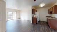 This single-floor residence offers a well-organized layout designed for comfortable everyday living. The open-concept living and dining area is finished with rich, dark wood-style flooring that extends throughout the main spaces, creating a cohesive and inviting atmosphere. A ceiling fan provides added comfort, while a sliding glass door allows natural light to flood the area. The kitchen is efficiently designed in a galley style, featuring warm wood cabinetry, granite-style countertops, a double-basin sink, and white appliances including an electric range, refrigerator, and microwave. The bedroom is carpeted for warmth and comfort, benefits from natural light through a window, and offers generous storage with dual closets. The full bathroom includes dark wood-style flooring that mirrors the main living area, a vanity with granite-style countertops set in rich wood cabinetry, a large mirror, and a full-size tub and shower combination. A dedicated laundry area houses a full-size side-by-side washer and dryer with overhead wire shelving, providing practical in-unit convenience. The overall design is clean and functional, with a neutral color palette throughout.