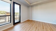 Located at 3929 Market St in Edina, MN, this single-floor unit showcases a thoughtfully designed modern interior with high-quality finishes throughout. The kitchen is a standout feature, outfitted with light gray shaker-style cabinetry, crisp white quartz countertops, a white subway tile backsplash, and stainless steel appliances including a gas range with a wall-mounted hood. Light hardwood-style flooring runs underfoot, while geometric black pendant lights add a contemporary accent above the island, which includes an undermount sink with a matte black faucet.

The bathroom continues the modern aesthetic with matching gray cabinetry, white quartz countertops, matte black hardware, large-format tile flooring, and a tiled tub-and-shower combination. A framed mirror and recessed lighting complete the clean, polished look.

Living and sleeping areas feature a mix of hardwood-style and plush carpet flooring, with neutral walls that complement the overall palette. Large black-framed windows flood the interior with natural light and offer open views of the surrounding Edina neighborhood. Multiple rooms provide direct access to an outdoor balcony through full-height black-framed glass doors, enhancing the connection between indoor and outdoor living.