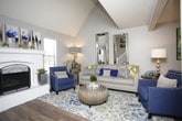 This two-story residence offers a thoughtfully designed layout with a variety of comfortable living spaces. The living room draws immediate attention with its vaulted ceiling, creating an airy, open atmosphere, and is anchored by a classic white-painted brick fireplace flanked by windows that allow natural light to fill the room. Rich hardwood-style flooring runs throughout the main living and dining areas, adding warmth and continuity. The dining area is positioned adjacent to a sliding glass door that opens to an outdoor patio, providing a seamless indoor-outdoor connection. The kitchen is outfitted with white cabinetry, granite countertops, a tile backsplash, and stainless steel appliances, offering both style and functionality. A half bathroom on the main level features a granite vanity and a framed mirror. Multiple bedrooms are carpeted and include ceiling fans, closets, and ample space for furnishings. The primary bedroom includes a dedicated closet and en-suite access. An additional full bathroom features a tub-shower combination with granite countertops. Throughout the home, neutral gray walls provide a versatile backdrop, and ceiling fans are present in the key living spaces, contributing to a comfortable and well-ventilated environment across both floors.