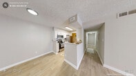 This 2-bedroom, 1-bathroom single-floor residence offers a practical and well-designed layout with a bright, neutral color palette throughout. The open-concept kitchen and living area serves as the heart of the home, featuring white shaker-style cabinetry, granite countertops, a white subway tile backsplash, and a full suite of stainless steel appliances including a refrigerator, range, and microwave. A peninsula provides additional counter space and separates the kitchen from the adjacent living area. Light wood-style flooring extends throughout the main living spaces, lending a clean and cohesive aesthetic. A central hallway connects the living areas to the bedrooms and bathroom. Both bedrooms are carpeted and feature ceiling fans with lighting, individual windows that allow natural light, and dedicated closets with wire shelving. The primary bedroom offers a comfortable, generously sized layout. The shared bathroom is finished with granite countertops, a framed mirror, and light wood-style flooring, with an adjacent open closet providing additional storage. Two closets are present throughout the unit, maximizing storage options. The textured ceilings and warm neutral tones create a cohesive and inviting atmosphere throughout the entire space.
