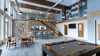 Located at 1 Kennedy Ave in Danbury, Connecticut, this two-story space makes a striking impression with its industrial-chic aesthetic and open, airy layout. Exposed brick walls, dark wood beam accents, and visible ductwork lend the interior a modern loft-like character, while large pendant lights hang from the soaring double-height ceiling, illuminating the space with warm, focused light.

The main floor is thoughtfully arranged for both social interaction and relaxation. A full-size pool table anchors one end of the room, providing a central recreational focal point. Adjacent to it, a bar-height counter lined with contemporary molded chairs faces a pair of mounted flat-screen TVs, creating an ideal setting for casual gatherings or watching live events. Traditional dining seating is also available nearby, offering additional flexibility for the space.

A sleek staircase with metal railings connects the main floor to the upper level, which overlooks the main area through an open mezzanine railing, enhancing the sense of vertical space and connectivity between floors. Built-in shelving on the upper level adds both functional storage and visual interest.

The light wood-toned flooring throughout ties the various zones together cohesively, while framed artwork on the walls adds personalized character. Overall, the space combines comfort, functionality, and a contemporary industrial style into a versatile, welcoming environment.