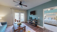 Located at 2889 Sollie Rd in Mobile, Alabama, this single-story home offers a thoughtfully designed layout with a cohesive coastal-inspired color palette of soft teals, creams, and warm wood tones throughout. The living room serves as the heart of the home, featuring rich hardwood-style flooring, a ceiling fan, a distinctive teal accent wall, and French doors that invite abundant natural light and outdoor access. The adjoining dining area is anchored by an elegant wrought-iron chandelier and provides a welcoming space for gatherings. The galley-style kitchen is well-equipped with stainless steel appliances, granite countertops, warm maple cabinetry, and a double sink — all connecting seamlessly to the dining space. A dedicated laundry room is conveniently accessible directly from the kitchen. The primary bedroom features plush carpeting, a teal accent wall, a ceiling fan, and access to natural light, while a second bedroom mirrors the same comfort and style. Two bathrooms serve the home: one with a tub-shower combo and clean white tile surround, and another featuring maple cabinetry, a granite vanity, a framed mirror, and a shower with curtain. Together, these spaces create a warm, well-organized home with consistent finishes throughout.