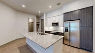 This well-appointed one-bedroom, one-bathroom residence in McKinney, Texas offers an efficiently designed single-floor layout with modern finishes throughout. The open-concept living, dining, and kitchen area serves as the heart of the home, centered around a generous granite-topped island with an undermount sink — ideal for both meal prep and casual dining. The kitchen is outfitted with white upper cabinetry, dark lower cabinetry, a herringbone tile backsplash, and a full suite of stainless steel appliances including a refrigerator with ice maker, built-in microwave, and range. Wood-style plank flooring runs throughout the main living areas, complementing the clean, neutral color palette. The living area benefits from natural light through blinds-fitted windows and access to an exterior door. The bedroom is a comfortable, well-proportioned retreat with its own window and access to two closets, including a walk-in closet with built-in shelving and hanging rods. The bathroom features a dark-cabineted vanity with granite countertop, a large mirror, subway tile tub/shower combination, and light tile flooring. A dedicated laundry area and hallway round out this thoughtfully planned residence.
