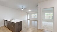 Located at 255 Cemetery Rd in Troy, NY, this well-designed 1-bedroom, 1-bathroom unit offers a clean, modern aesthetic throughout its single-floor layout. The open-concept kitchen and living area serves as the heart of the home, featuring light hardwood-style flooring, crisp white walls, and a ceiling fan that enhances airflow and comfort. The kitchen is equipped with stainless steel appliances — including a refrigerator, range, and microwave — complemented by light gray cabinetry and a peninsula with a white countertop and undermount sink, providing both workspace and a casual dining option. Large windows and a glass door in the living area invite abundant natural light and offer views of the surrounding greenery. A wall-mounted mini-split unit ensures climate control year-round. The spacious bedroom is carpeted for warmth and comfort, featuring a large window with outdoor views and ample room for furnishings. An adjacent walk-in closet offers built-in wire shelving for organized storage. The full bathroom includes a vanity with storage, toilet, and a tub/shower combination, all finished with consistent light hardwood-style flooring. A connecting hallway ties the layout together cleanly, making this a thoughtfully designed and move-in-ready space.