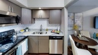 Located at 1521 Hickory Valley Rd in Chattanooga, TN, this single-floor residence offers a well-appointed layout designed for comfortable everyday living. The kitchen is a standout feature, showcasing gray flat-front cabinetry, granite-look countertops, a classic white subway tile backsplash, and a full suite of stainless steel appliances including a refrigerator, range, over-the-range microwave, and dishwasher. Rich hardwood-style flooring ties the kitchen seamlessly into the rest of the living spaces. The living room is bright and inviting, centered around sliding glass doors that open to a private balcony, allowing natural light to fill the space. Neutral-toned walls and dark hardwood-style flooring create a warm, cohesive aesthetic throughout. The bedroom is generously sized, featuring plush carpeting, a ceiling fan with light fixture, and a window dressed with curtains that soften the natural light. The room offers ample space for large furniture and includes closet access. The bathroom continues the home's modern design language with gray cabinetry, granite-look countertops, and a shower-tub combo. Overall, the residence presents a clean, contemporary aesthetic with consistent finishes throughout.