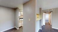 Located at 8819 E Valley Ranch Pkwy in Irving, TX, this two-bedroom, one-bathroom unit offers a practical and comfortable single-floor layout. Dark hardwood-style flooring runs consistently throughout the space, creating a cohesive look from room to room.

The combined kitchen and living area serves as the heart of the unit. The kitchen is equipped with white cabinetry, a white electric range, a dishwasher, and speckled countertops, with a peninsula-style breakfast bar that opens toward the living area. The living room receives natural light through a sliding glass door that leads to a private balcony with outdoor views, adding a sense of openness to the space.

Both bedrooms feature ceiling fans with light fixtures and sliding-door closets offering practical storage. The primary bedroom is a comfortable size and includes a window with views of the surrounding greenery. The second bedroom similarly benefits from natural light via a large window. A connecting hallway links the bedrooms to the full bathroom, which includes a tiled shower/tub combination, a toilet, and overhead cabinetry with a speckled countertop vanity. Neutral gray tones on the walls throughout the unit provide a clean and versatile backdrop.