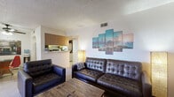 Located on East Highland Avenue in Phoenix, Arizona, this single-floor residence offers a practical and well-organized layout with two bedrooms, two bathrooms, a living room, dining room, and an in-unit laundry area. The living room features carpeted flooring, a textured ceiling, and an open sightline to the kitchen, which is accessible via a pass-through counter with warm wood cabinetry. The space is well-lit and inviting. The dining area is finished with tile flooring and features a ceiling fan overhead, creating a comfortable setting for everyday meals. The primary bedroom includes a ceiling fan, plush carpet, a mirrored sliding-door closet, and a sliding door that brings in natural light. The second bedroom also features carpet and a ceiling fan, offering a functional space with room for a desk and sleeping arrangement. Both bathrooms include a vanity with wood cabinetry and a tub-shower combination. One bathroom features tile accents, while the other offers a clean, neutral finish. Throughout the home, textured ceilings and tile or carpet flooring provide a consistent and cohesive aesthetic. The layout makes efficient use of space, providing all essential rooms within a compact and manageable footprint.