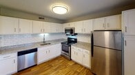 Located at 201 Cairn Cir in Knoxville, Tennessee, this single-floor residence offers a well-organized layout with a range of updated finishes throughout. The kitchen stands out as a highlight, featuring crisp white shaker cabinetry, granite-look countertops, a classic white subway tile backsplash, stainless steel appliances including a range, microwave, refrigerator, and dishwasher, and durable wood-look flooring. The living area is generously proportioned, with neutral-toned carpet, soft gray walls, and a textured ceiling. A sliding glass door opens to a private balcony, allowing natural light to fill the space and providing an outdoor view. The bedroom areas are carpeted and painted in neutral tones, each offering closet storage — including a bifold closet with a hanging rod in one bedroom and a walk-in closet accessible through the bathroom in another. The bathroom features a granite-top vanity with an undermount sink, wood-look flooring, and direct access to the walk-in closet. Hallways connect the rooms efficiently, and a thermostat is conveniently positioned in the main corridor. Textured ceilings are consistent throughout, giving the space a cohesive, finished appearance.