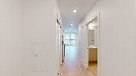 Located at 4520 California Ave SW in Seattle's vibrant West Seattle neighborhood, this thoughtfully designed one-bedroom, one-bathroom residence offers a clean, modern aesthetic throughout its single-floor layout. Light hardwood-style flooring flows seamlessly across every room, complementing the crisp white walls and recessed lighting that create a bright, airy atmosphere.

The open kitchen is outfitted with stainless steel appliances — including a dishwasher, microwave, and range — paired with two-tone cabinetry featuring light wood uppers and sleek gray lower cabinets, all anchored by a contemporary white countertop with an undermount sink. The kitchen opens directly to the living area, enhancing the sense of space.

A well-lit hallway connects the main living area to the private bedroom, which features a large window with views of the surrounding neighborhood, two closets with sliding doors, and ample room to furnish comfortably. The bathroom includes light wood cabinetry, a vanity with sink, and accessibility grab bars. A dedicated laundry area with a stacked full-size washer and dryer adds everyday convenience. Two closets provide generous storage throughout the unit. The overall design is clean, functional, and move-in ready.