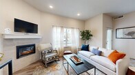 Located at 61560 Aaron Way in Bend, Oregon, this well-appointed 1-bedroom, 2-bathroom home offers an efficient and thoughtfully designed single-floor layout. The living room serves as the heart of the space, featuring a tiled fireplace with a clean white mantle, recessed lighting, warm wood-look flooring, and large windows dressed with sheer curtains that invite abundant natural light and views of the surrounding neighborhood. The kitchen is equipped with stainless steel appliances, gray shaker-style cabinetry, granite-style countertops, and a breakfast bar with seating — ideal for casual dining. A sliding barn door leads to an in-unit laundry area, adding everyday convenience. The bedroom offers plush carpet, a vaulted ceiling accent, and a private door with direct outdoor access to a patio. Two full bathrooms serve the home, including one en-suite bathroom off the bedroom featuring tile flooring, a walk-in shower with glass enclosure, and a vanity with granite countertops. A dedicated closet provides organized storage. Neutral tones and modern finishes throughout create a clean, cohesive aesthetic well-suited to comfortable living in Central Oregon.