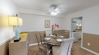 This classic two-bedroom, one-and-a-half-bath residence is thoughtfully laid out on a single floor, offering a functional and comfortable living environment. The living room is generously sized, featuring neutral carpet flooring, clean white walls, and a sliding glass door that invites natural light and provides outdoor access. The open sightline into the adjacent dining area creates a cohesive flow between the two spaces.

The dining room features a ceiling fan with light fixture, warm two-tone walls with a chair rail detail, and carpeted flooring that continues from the living area. It connects directly to the kitchen, which is equipped with white cabinetry featuring gold hardware, dark granite-style countertops, a coil-burner range, and a stainless steel sink — providing ample workspace and storage.

Both bedrooms offer comfortable proportions with carpet flooring, neutral walls, and closet access. The full bathroom includes a vanity with a mirrored medicine cabinet and tile flooring, while the half bath provides a compact, clean layout with matching tile flooring and white fixtures. In-unit laundry is also available, adding everyday convenience to this well-appointed classic floor plan.