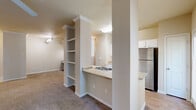 Located at 1 Stonebridge Cir in Little Rock, Arkansas, this well-appointed two-bedroom, two-bathroom residence offers a thoughtfully designed single-floor layout. The living room is generously sized, featuring plush carpeting, crown molding, and a ceiling fan, with multiple windows that invite natural light and views of the surrounding area. The kitchen is positioned adjacent to the living space and features a pass-through counter with a sink, white cabinetry, a stainless steel refrigerator, and hard surface flooring that contrasts nicely with the carpeted living areas. A distinctive built-in shelving unit serves as a functional and decorative divider between the main living areas. The primary bedroom offers a comfortable footprint with soft carpeting, a ceiling fan, and access to a dedicated closet. The second bedroom also features carpeting, a ceiling fan, and its own closet. Both bathrooms are finished with tile surrounds, tub-shower combinations, white vanity cabinetry, and warm-toned countertops. Additional highlights include a dedicated laundry area, a utility room, a built-in desk nook with overhead cabinetry, and ample storage throughout with multiple closets and hallways connecting the rooms seamlessly.