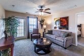 This single-floor, 2-bedroom, 2-bathroom residence in Jeffersonville, Indiana, offers a thoughtfully designed layout that maximizes comfort and functionality. The living room serves as the heart of the home, featuring plush carpeting, a ceiling fan, and a glass-paneled door that invites natural light and outdoor views. The space flows seamlessly into a dedicated dining area, illuminated by an elegant multi-bulb chandelier and accented by warm, neutral tones throughout.

The kitchen is well-equipped with rich cherry-toned cabinetry, granite-look countertops, a full suite of black appliances including a refrigerator, range, and built-in microwave, and durable tile flooring. A pass-through counter connects the kitchen to the dining area, enhancing the open feel of the common spaces.

Both bedrooms are generously sized with soft carpeting and ceiling fans. Each offers closet storage, and the rooms are brightened by windows with outdoor views. The two full bathrooms feature tile flooring and tub-shower combinations, providing practical convenience.

Throughout the home, a consistent warm, neutral color palette, textured ceilings, and tasteful architectural details create a cohesive and inviting atmosphere suited for comfortable everyday living.