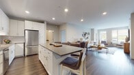 This thoughtfully designed single-floor residence offers a seamless blend of modern style and functional living. The open-concept layout connects the kitchen and living area, creating a bright, expansive feel. The kitchen is a standout, featuring white shaker cabinetry, stainless steel appliances including a gas range, microwave, and refrigerator, a white subway tile backsplash, and a generously sized island with quartz-style countertops and bar seating — ideal for both cooking and casual dining. Rich hardwood-style flooring flows throughout the main living areas, grounding the space with warmth and contrast.

The living room is light-filled, benefiting from large windows that invite natural light and provide outdoor views. Neutral walls and contemporary décor, including distinctive wall art, lend the space a curated, welcoming ambiance.

The bedrooms are carpeted for comfort, with the primary bedroom offering generous proportions, large windows with ample natural light, and space for a sitting area. Additional bedrooms are well-appointed with clean lines and neutral tones.

The bathroom features a dual-sink vanity with dark-framed mirrors, quartz-style countertops, white cabinetry, a tall linen tower, and hardwood-style flooring, delivering a polished, spa-like atmosphere. Overall, this residence combines modern finishes with a cohesive, comfortable design.