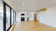 This contemporary unit at 6105 Almon Street in Halifax, Nova Scotia, offers a clean, modern aesthetic with thoughtful design throughout. The open-concept kitchen and living area forms the heart of the space, showcasing a sleek, all-white kitchen with high-gloss cabinetry extending to the ceiling, stainless steel appliances including a range, dishwasher, and refrigerator, and a bright white countertop with tile backsplash. Light-toned hardwood flooring runs seamlessly across the entire unit, enhancing the sense of openness and continuity. Large floor-to-ceiling windows and a sliding glass door in the living area invite abundant natural light and provide access to a private balcony. A well-lit hallway connects the living space to the private bedroom, which is comfortably sized and features recessed lighting, a large window, and direct balcony access. A dedicated closet offers convenient storage. The two full bathrooms are finished in neutral, light-toned tile, each featuring a glass-enclosed walk-in shower, modern vanity, and clean, minimalist fixtures. Recessed lighting throughout the unit and brushed gold door hardware add refined finishing touches to this bright, move-in-ready space.
