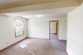 Located at 900 Wigwam Hollow Rd in Macomb, Illinois, this single-floor, two-bedroom, one-bathroom unit offers a practical and comfortable layout. The open-concept kitchen and living area serves as the heart of the home, where warm hardwood-style flooring flows through the kitchen zone and transitions into carpet in the living area. The kitchen is equipped with warm wood cabinetry, a white electric range, refrigerator, and a single-basin sink, providing all essential amenities in a clean, functional arrangement. The living area offers ample space for everyday use. Both bedrooms are carpeted and finished with neutral cream-toned walls and warm wood trim, creating a clean and inviting atmosphere. The primary bedroom is generously sized and includes a sliding closet, while the secondary bedroom benefits from a large window that fills the room with natural light and offers views of the surrounding greenery. Each bedroom features wood-framed windows with blinds. The full bathroom includes a tub/shower combination, a wood-vanity with countertop sink, and hardwood-style flooring, maintaining the warm aesthetic found throughout. A dedicated laundry area with a washer and dryer is accessible from one of the bedrooms, adding a convenient in-unit feature. The unit presents a straightforward, well-maintained living space suitable for comfortable day-to-day living.