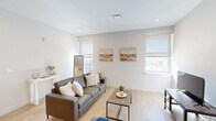 Located at 237 William Howard Taft Rd in Cincinnati's Corryville neighborhood, this thoughtfully designed unit offers four bedrooms and two bathrooms across a single floor. The open-concept layout connects the kitchen and living room, creating a cohesive and functional common area. The living room is bright and welcoming, with multiple windows fitted with roller shades that allow natural light to fill the space, complemented by light wood-style flooring that runs throughout.

The kitchen is a standout feature, centered around a generous island with a white quartz countertop, undermount sink, and bar seating for multiple guests. Rich dark-toned cabinetry pairs with stainless steel appliances, including a range, microwave, and refrigerator, offering both style and practicality.

Each bedroom is comfortably sized and includes a sliding-door closet with built-in shelving, providing efficient storage. The clean, neutral palette of the bedrooms creates a calm and restful atmosphere. Both bathrooms echo the unit's modern aesthetic, featuring wood-toned vanities and a tub-shower combination with a curtain rod.

Additional conveniences include a dedicated laundry area, multiple hallways connecting the rooms efficiently, and recessed lighting throughout, making this a well-appointed and highly functional home.