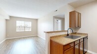 Located at 8495 Bella Woods Drive in Lewis Center, Ohio, this one-bedroom, one-bathroom home offers a well-organized layout designed for comfortable everyday living. The open-concept kitchen and living area form the heart of the home, finished with light wood-style flooring that runs throughout. The kitchen is equipped with warm medium-tone cabinetry, granite-style countertops, black appliances including a refrigerator, electric range, and built-in microwave, as well as a single-basin sink. A stylish pendant chandelier illuminates the transition between the kitchen and living area, adding a decorative touch to the space. The living area provides a bright, open canvas with neutral warm-beige walls, clean white baseboards, and a window that invites natural light. The bedroom is a comfortable retreat featuring plush carpeting, a ceiling fan with integrated lighting, and a window with blinds offering a view of the outdoors. A dedicated closet provides convenient storage. The bathroom includes a full-size soaking tub and shower combination with a clean white surround, complemented by wood-style flooring. A hallway connects the main living spaces to the private areas of the home, creating a practical and cohesive flow throughout.