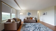 This single-floor residence offers a thoughtfully designed layout that balances comfort and functionality across its key living spaces. The living room serves as the heart of the home, featuring warm hardwood flooring, an exposed ceiling beam, and large windows that invite generous natural light. Neutral-toned walls complement the open feel of the space, which connects seamlessly to the rest of the unit.

The kitchen is outfitted with stainless steel appliances, including a gas range, built-in microwave, and refrigerator, all set against crisp white cabinetry and light countertops. Rich hardwood flooring continues throughout, adding warmth to the galley-style layout.

The dining area is a standout space, highlighted by a modern chandelier and a sliding glass door that opens to a private outdoor balcony with tree-lined views, creating an ideal setting for everyday dining or entertaining.

The primary bedroom is generously sized with plush carpeting, large windows, and ample natural light. A secondary bedroom also features carpet flooring and closet storage. A spacious walk-in closet with multi-level rods provides abundant storage. The bathroom is finished with a white vanity, clean countertop, and hardwood flooring, offering a crisp, functional design.