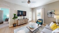 This 610 square foot apartment in Noblesville, Indiana, offers a well-designed living space that maximizes functionality and style. The single-floor layout features one bedroom measuring 140 square feet, one bathroom, and an open-concept kitchen and living area. The interior boasts a modern aesthetic with a cohesive color scheme of neutral tones accented by pops of teal and yellow.

The living room is bright and inviting, with large windows allowing ample natural light. It's furnished with a comfortable grey sofa, accent chairs, and a sleek coffee table. A striking teal feature wall adds depth and character to the space. The adjacent kitchen is equipped with white cabinetry, stainless steel appliances, and ample counter space, perfect for preparing meals.

The bedroom continues the contemporary theme with a teal accent wall, plush carpeting, and a large window. A ceiling fan provides comfort, while the dresser and closet offer storage solutions. The bathroom, though compact, is efficiently designed with a vanity and modern fixtures.

Throughout the apartment, thoughtful details like artwork, plants, and decorative objects create a homey atmosphere. The light wood flooring in the main living areas contrasts beautifully with the carpeted bedroom, adding warmth and texture. Despite its modest size, this apartment feels spacious and well-proportioned, ideal for comfortable single living or a cozy couple's retreat.