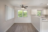 Located at 530 W First St in Tustin, California, this 2-bedroom, 1-bathroom single-floor unit offers a practical and comfortable layout designed to maximize its well-proportioned footprint. The open-concept living, dining, and kitchen area forms the heart of the home, where light wood-style flooring flows seamlessly into the kitchen and transitions to plush carpeting in the living space. A ceiling fan with lighting overhead adds both style and function to this combined area.

The kitchen is well-equipped with ample white cabinetry, generous counter space featuring speckled laminate countertops, a double-basin stainless steel sink, and a gas range. A peninsula divides the kitchen from the dining and living areas, and a window above the sink brings in natural greenery views. Vertical blinds throughout the unit allow for flexible light control.

Both bedrooms are carpeted and feature ceiling fans, closets, and windows with outdoor views, lending each room a bright and airy feel. The primary bedroom offers a comfortable and private retreat. Three closets throughout the unit provide practical storage solutions.

The bathroom includes a full tub-shower combo with white tile surround, a pedestal sink, and a small operable window for ventilation. A hallway connects the living areas to the bedrooms and bath, keeping the layout organized and efficient.