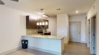 This one-bedroom, one-bathroom residence at Gadsden in Cayce, SC offers a modern and cohesive design across a single floor. The open-concept layout connects the kitchen, dining, and living areas seamlessly, creating an efficient and inviting flow throughout the space.

The kitchen serves as a focal point, showcasing granite countertops, dark espresso cabinetry, a subway tile backsplash, and stainless steel appliances including a range, microwave, and dishwasher. A peninsula with an undermount sink and pendant lighting above doubles as a casual dining or prep surface, while track lighting adds additional functionality overhead.

The living and dining area is bright and open, benefiting from natural light through a large window fitted with blinds and a ceiling fan for year-round comfort. Wood-look flooring runs throughout the main living spaces, lending a clean and contemporary aesthetic.

The bedroom is a comfortable retreat, finished with plush carpeting, a ceiling fan with light, and panel-style doors leading to a dedicated closet. A secondary room with wood-look flooring and a window provides additional flexible space.

The bathroom is finished with granite countertops, dark cabinetry matching the kitchen, a tub-shower combination, built-in open shelving, and wood-look tile flooring, maintaining a consistent design language throughout the home.