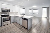 Located at 460C Belmont Ave in Kitchener, Ontario, this well-designed two-bedroom unit offers a thoughtfully arranged single-floor layout. The open-concept kitchen and living area serves as the heart of the unit, featuring a large peninsula with a white quartz countertop and double sink, white upper cabinetry, grey lower cabinets, and a full suite of stainless steel appliances including a refrigerator, electric range, and built-in microwave. Recessed pot lights illuminate the kitchen, while the adjoining living area benefits from multiple windows fitted with roller blinds, allowing ample natural light.

Light-toned laminate wood flooring runs consistently throughout the unit, complementing the neutral colour palette of warm grey and crisp white walls. The primary bedroom provides comfortable proportions alongside a dedicated closet. The second bedroom also features a window with an outdoor view of surrounding greenery. Both rooms are finished with clean white panel doors and white trim baseboards. A hallway connects the main living spaces to the bedrooms, with a bathroom conveniently accessible. The overall design is clean, contemporary, and move-in ready.