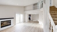 This two-story home offers a well-designed layout across two floors, combining functional living spaces with modern finishes throughout. The main floor opens into a bright, airy living area distinguished by soaring ceilings and an open upper-level balcony railing that adds architectural depth. Light hardwood-style flooring runs throughout the main level, and a large sliding glass door fills the living space with natural light while providing access to the outdoor area. The kitchen is well-appointed with rich dark wood cabinetry, white countertops, a full suite of stainless steel appliances, a skylight, and a tile backsplash — offering both style and practicality. A fireplace feature adds a focal point to the living area, and a full bathroom on the main floor includes a tub/shower combination with stylish linear tile and matte black fixtures. Upstairs, the upper floor houses all three bedrooms, including a generously sized primary bedroom with its own en-suite bathroom and dedicated closet. The secondary bedrooms feature plush carpeting, textured ceilings, and natural light from operable windows. The second bathroom is clean and efficiently designed with a dark wood vanity and a well-lit mirror. A staircase with a white balustrade connects the two floors seamlessly, rounding out this well-organized and move-in-ready home.