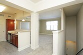 This single-floor residence offers a thoughtfully designed layout that balances comfort and functionality throughout. The open living area features plush carpeting, crown molding, and a columned peninsula that connects seamlessly to the kitchen, creating an inviting and cohesive common space. A pendant light accents the kitchen pass-through, while warm-toned cabinetry, light countertops, and stainless steel appliances — including a refrigerator and electric range — give the kitchen a clean, practical character. Light vinyl flooring runs through the kitchen and bathroom, providing easy maintenance in high-traffic areas. The full bathroom is outfitted with a vanity featuring rich wood cabinetry, a toilet, and a soaking tub with a shower combination, all finished in neutral tones. Multiple bedrooms are carpeted and filled with natural light through sizable windows with blinds. One bedroom includes a ceiling fan, while another benefits from crown molding, echoing the refined detailing found in the living area. A generously sized walk-in closet with wire shelving and carpeted flooring provides ample storage. Throughout the residence, neutral wall colors and consistent finishes create a cohesive, move-in-ready atmosphere.