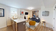 Located at 2874 Colerain Ave in Cincinnati, OH, this efficiently laid-out one-bedroom, one-bathroom unit offers a complete set of living spaces across a single floor. The open-concept kitchen is a standout feature, equipped with stainless steel appliances including a full-size refrigerator, electric range, and built-in microwave. Warm-toned cabinetry with gold hardware pairs elegantly with quartz countertops and a kitchen island with bar seating, making it both functional and visually appealing. Light hardwood flooring flows throughout the kitchen and main living areas, enhancing the bright, airy feel. The living room offers a comfortable and contemporary setting, with neutral walls, carpeted flooring, and natural light filtering through windows. The bedroom is a calm retreat, carpeted and naturally lit, featuring a spacious closet and framed wall art. The bathroom is a design highlight, showcasing intricate patterned tile flooring, a marble-surround glass-enclosed shower, a floating vanity with gold fixtures, and a backlit mirror — all combining to create a spa-like ambiance. This well-appointed unit balances modern style with practical living in a compact, efficient footprint.