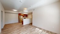 Located at 1650 Huntington Dr in Roseville, CA, this single-story, two-bedroom, one-bathroom residence offers a well-organized and functional layout. Light wood-style flooring flows throughout the main living areas, lending a clean and cohesive aesthetic. The open-concept living, dining, and kitchen area forms the heart of the home, with a peninsula counter featuring a white quartz surface and an integrated sink. The kitchen is equipped with rich warm-toned cabinetry, stainless steel appliances including a refrigerator, range, and microwave, providing a practical and attractive workspace. Large windows and a glass door in the living area invite generous natural light and offer views of the surrounding greenery outside. The hallway connects the main living space to both bedrooms, each carpeted for comfort. The primary bedroom includes a double-door closet, while an additional closet with louvered doors provides extra storage along the hallway. The bathroom features a warm wood-toned vanity with white countertop, a large mirror, and a walk-in shower with built-in shelving. A dedicated laundry area rounds out the home's practical amenities, completing a thoughtfully designed living space.