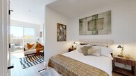 Located on West Colfax Avenue in Denver, Colorado, this thoughtfully designed one-bedroom, one-bathroom unit offers a modern aesthetic throughout its efficiently arranged single-floor layout. Light wood-tone flooring flows continuously across all rooms, complementing the crisp white walls and clean architectural lines that define the space.

The living room provides a comfortable retreat, featuring a closet, ample wall space for art display, and natural light that enhances the open feel. A private balcony extends the living area outdoors, offering views of the surrounding Denver neighborhood.

The kitchen is well-appointed with stainless steel appliances including a refrigerator, range, microwave, and dishwasher, alongside warm wood cabinetry with open shelving accents and a white countertop sink — a functional and stylish space for cooking.

The bedroom accommodates a queen-sized bed comfortably, with white walls, recessed lighting, and direct sightlines to the living area, creating a connected yet defined sleeping space. Two closets provide generous storage throughout the unit.

The bathroom features a floating wood-toned vanity with a white countertop, black matte fixtures, a round mirror, and a glass-enclosed walk-in shower with white tile surround and a built-in bench. In-unit laundry and a dedicated utility room add everyday convenience to this polished Denver residence.