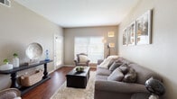 This single-floor residence offers a thoughtfully designed layout that balances comfort and functionality across several well-defined living spaces. The living room serves as the heart of the home, featuring rich hardwood-style flooring, warm neutral-toned walls, and large windows with horizontal blinds that allow abundant natural light to fill the space. A glass-paned entry door further enhances the bright, open ambiance.

Adjacent to the living area, the dedicated dining space is defined by a pendant light fixture overhead and direct access to the kitchen, creating a seamless flow for everyday living and entertaining. The kitchen is equipped with light wood cabinetry, granite-style countertops, a stainless steel dishwasher, and a double-basin sink — all set against the same hardwood-style flooring that runs throughout the main areas.

The primary bedroom features vaulted ceiling details, a ceiling fan, and a large window that invites natural light, while a second bedroom offers carpeted flooring and generous wall space. The full bathroom includes a wide vanity with granite-style countertops, a large mirror, and a shower-tub combination. Neutral, earthy tones and consistent finishes throughout the space contribute to a cohesive and welcoming atmosphere.